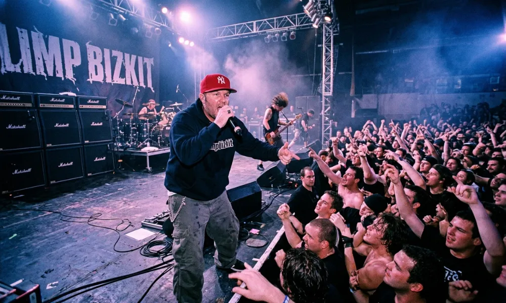 Facezem | Fred Durst Net Worth: How the Limp Bizkit Frontman Built His Fortune, Career and Legacy Fred Durst singing into a microphone in front of a energetic concert crowd