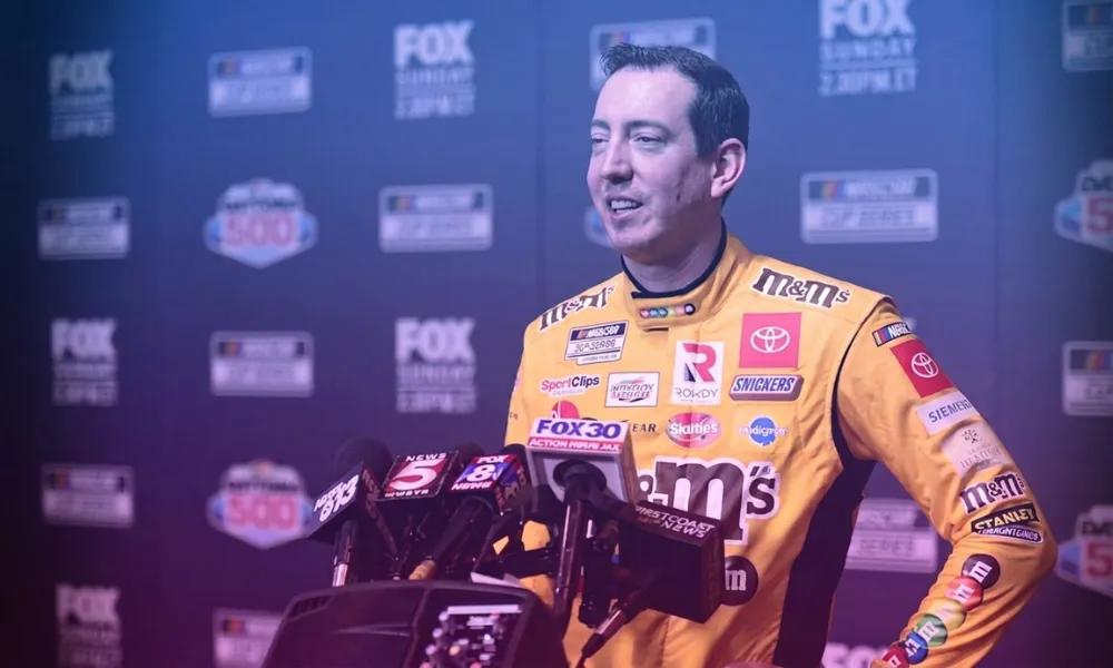 Kyle Busch speaking to press in his M&Ms sponsor firesuit