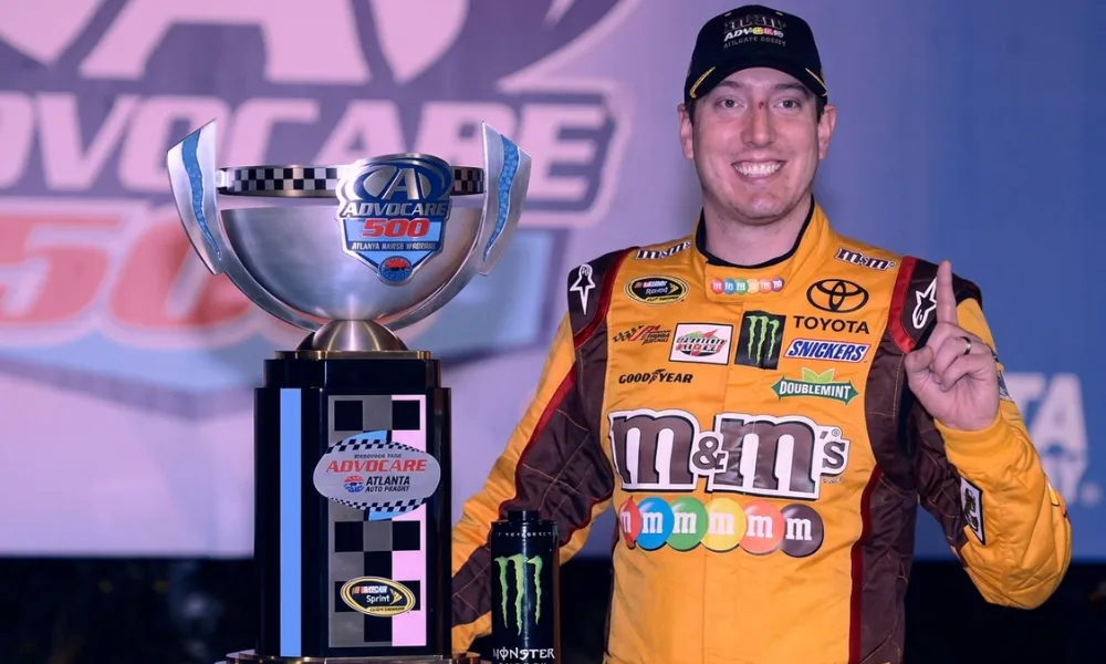 Kyle Busch posing with a race victory trophy in victory lane