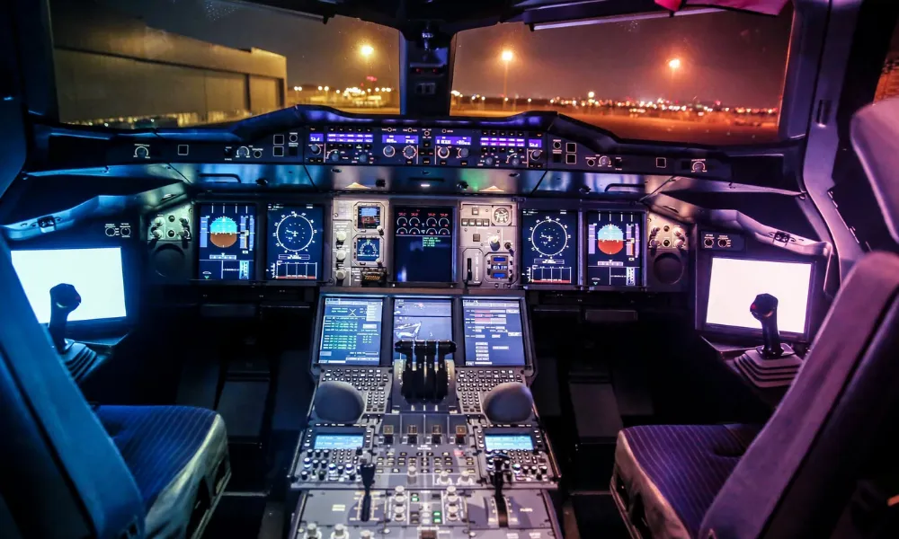 The illuminated dashboard and flight instruments inside a modern commercial aircraft cockpit at night.