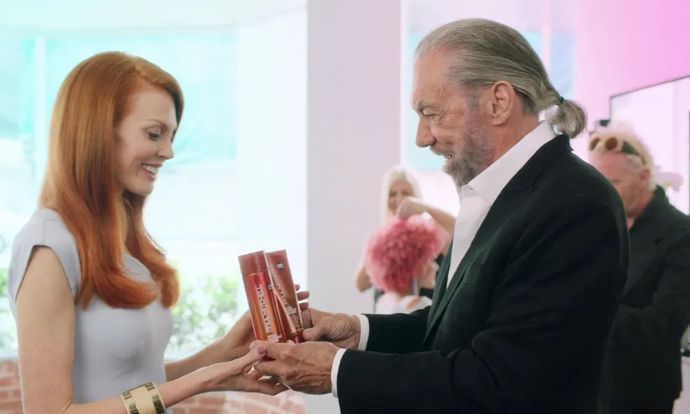 John Paul DeJoria presenting hair-care products in a salon setting.