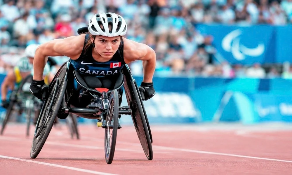 A female wheelchair athlete racing intently on a track during the Paralympic Games.