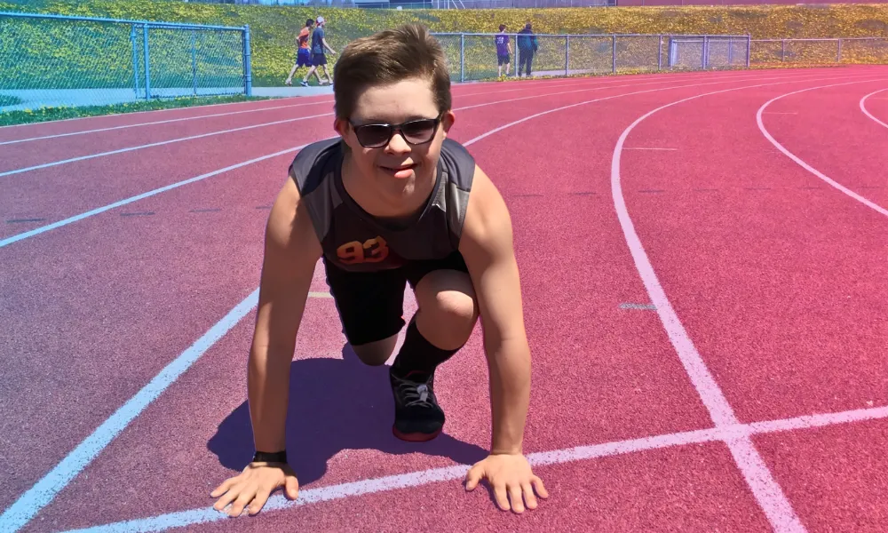 Chris Nikic in athletic wear positioned at the starting line of a running track.