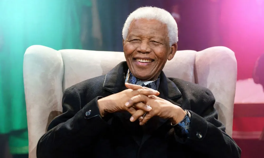 Nelson Mandela smiling while seated in an armchair during a public appearance-Real Life Inspiring Stories