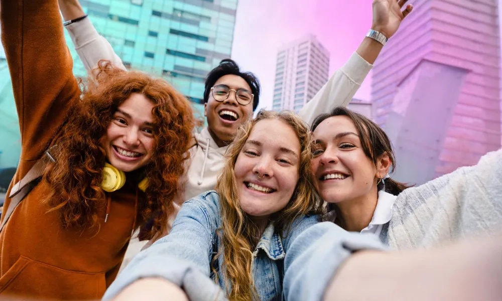 A group of happy young friends taking a selfie together outdoors in a city-Gen Z Slang