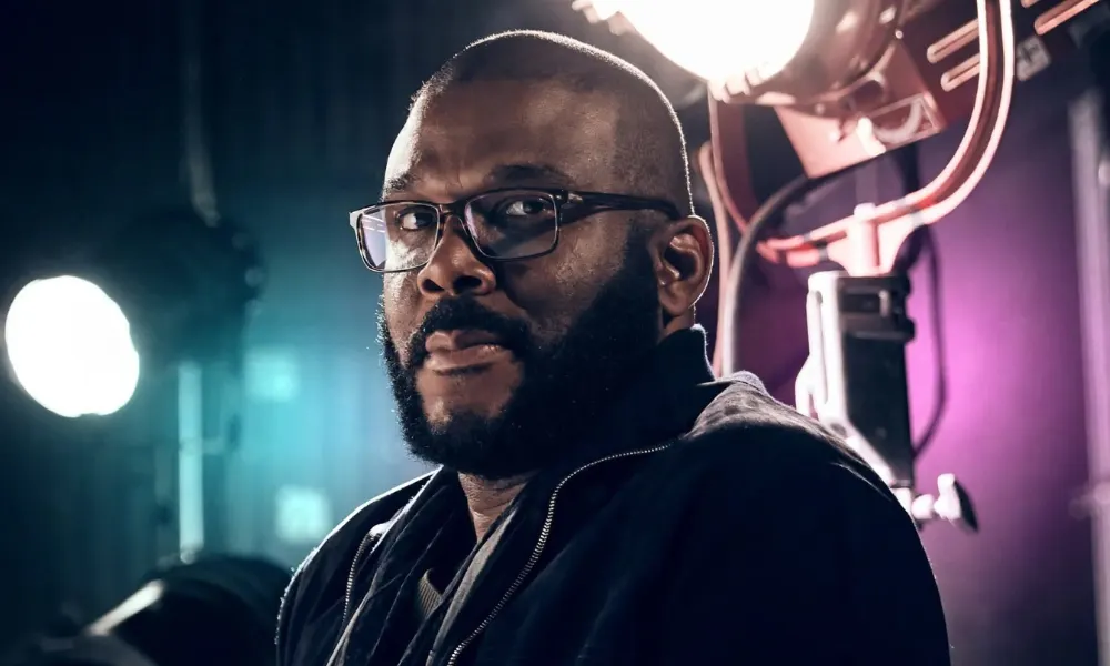 Tyler Perry on a production set with studio lighting behind him.